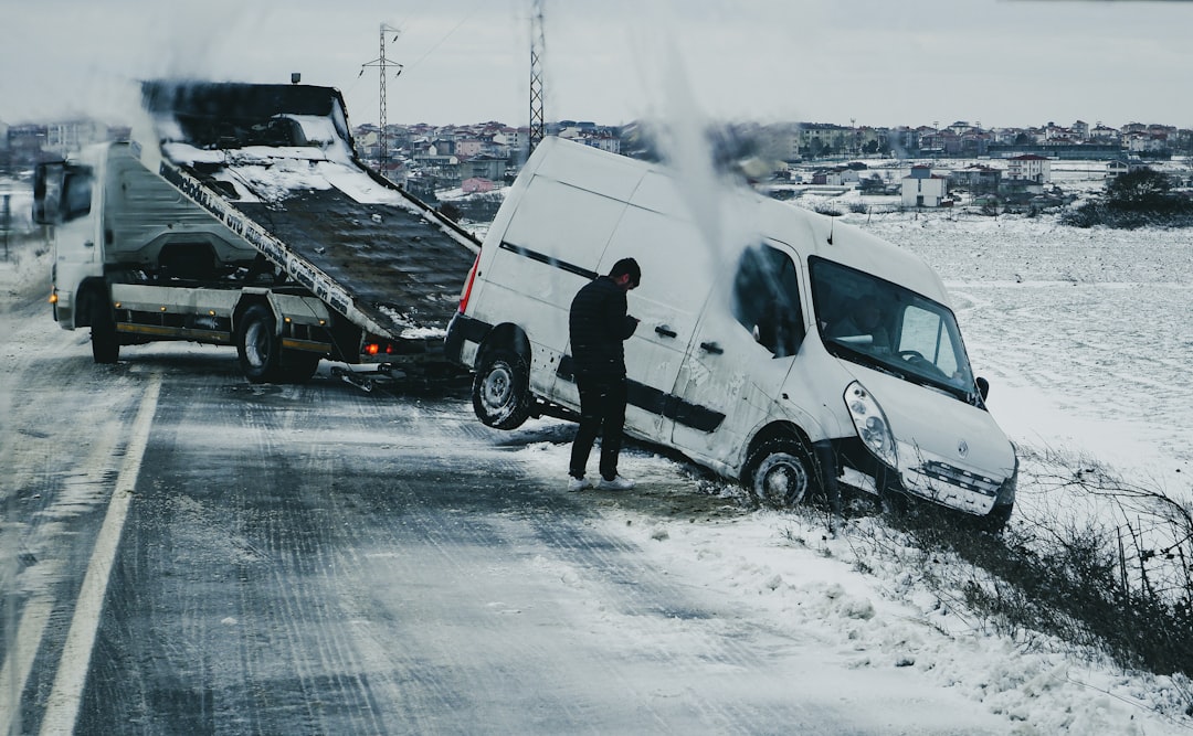a-man-standing-next-to-a-white-van-on-the-side-of-a-road-oi7meeg78k